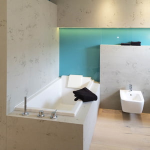 Badezimmer mit Badewannen- und Wandverkleidung in imi-beton Glattschalung grau und blaue Farbakzente an der Wand